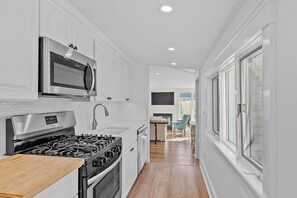 Cocina moderna con armarios blancos, electrodomésticos de acero inoxidable y encimera de madera.