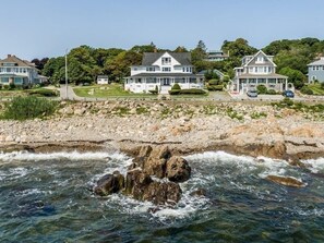 Una propiedad costera con varias casas, un litoral rocoso y una vista despejada del océano.