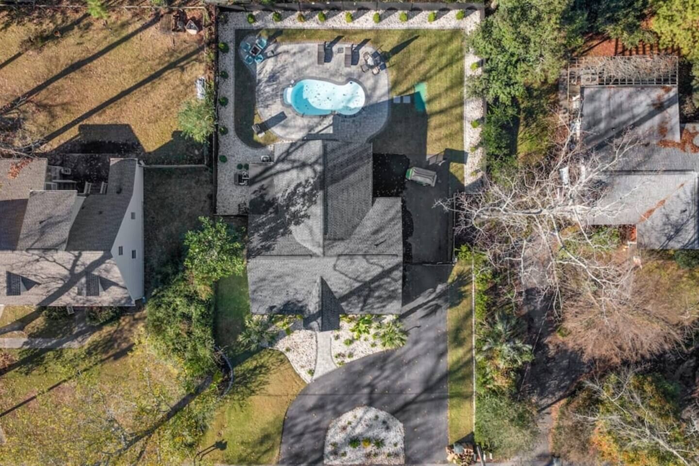 An aerial view of a property with a swimming pool, outdoor seating, and a large garden area.