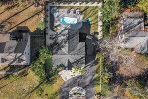 An aerial view of a property with a swimming pool, outdoor seating, and a large garden area.