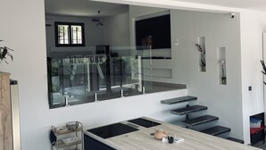 A modern kitchen with a central island, built-in appliances, and a view of the street through a large window.