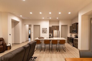 A modern kitchen with a central island, stainless steel appliances, and a dining area with a sofa and chairs.