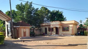 A residential area with two houses, a paved driveway, and a motorcycle parked in front of one house.