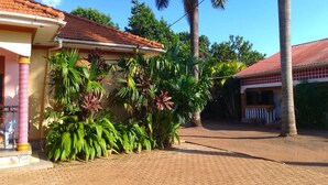 A house with a tiled roof, a paved driveway, and lush tropical plants.