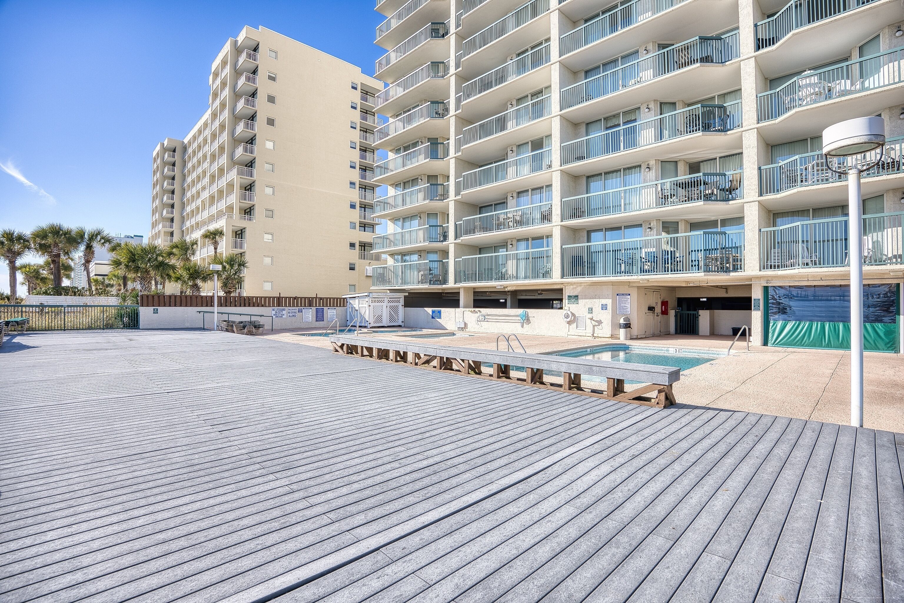 Un hôtel à plusieurs étages doté de balcons, d’un espace piscine et d’une terrasse en bois.