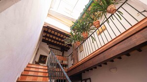 A staircase with a wooden handrail and metal balusters, leading to a balcony with potted plants. - Historic House in the City Center (Sevilla)