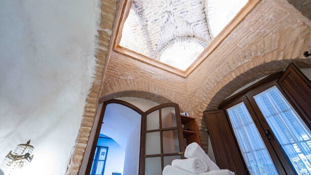 A room with a skylight, wooden door, and a towel stack. - Historic House in the City Center (Sevilla)