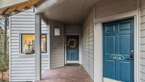 Et hus med blå dør, hvide vægge og en overdækket veranda.