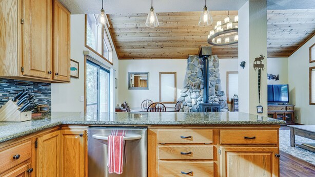 Une cuisine avec des armoires en bois, un lave-vaisselle en acier inoxydable et un mur décoratif en pierre.