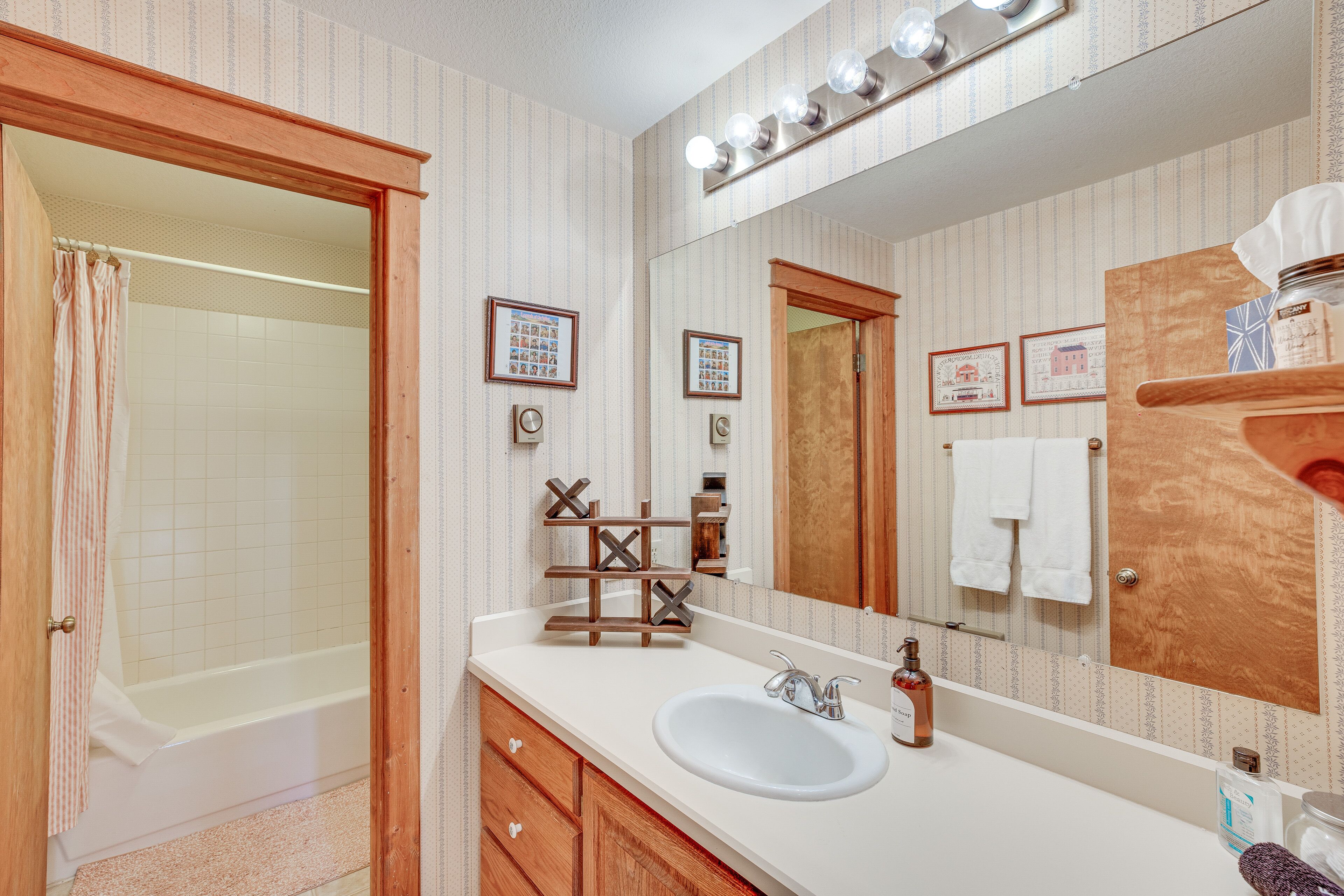 Une salle de bain avec une baignoire, un lavabo, un miroir et des meubles en bois.