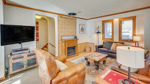 A living room with a fireplace, leather sofas, a television, and a coffee table. - Spacious Ouray Townhome - Walk to Hot Springs! (Ouray)