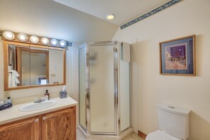Une salle de bain avec un meuble-lavabo, une cabine de douche en verre et des toilettes.