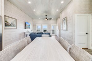 A long dining table with benches, a ceiling fan, and framed artwork on the walls. - Ahoy Matey Sp151 4 Bedroom Home by RedAwning (Fulton)