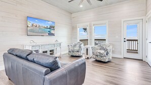 A spacious living area with a gray leather sofa, two patterned armchairs, a white console table, and a ceiling fan. - Ahoy Matey Sp151 4 Bedroom Home by RedAwning (Fulton)