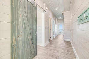 Um corredor com piso e paredes de madeira, que leva a uma porta com design rústico.