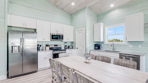 A modern kitchen with white cabinets, stainless steel appliances, and a large island with chairs.