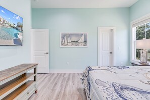 Relax in a serene space with a comfortable bed, a wall-mounted TV, and a beautiful sailboat painting.