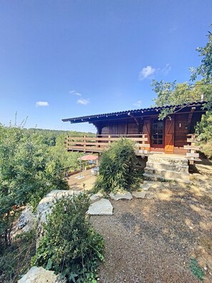 Situated in a lush environment, this cabin features a front porch with steps and a covered seating area.