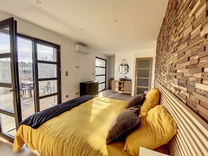 Relax in this serene bedroom with a large bed, sliding glass door to an outdoor area, and a wooden dresser with a mirror.
