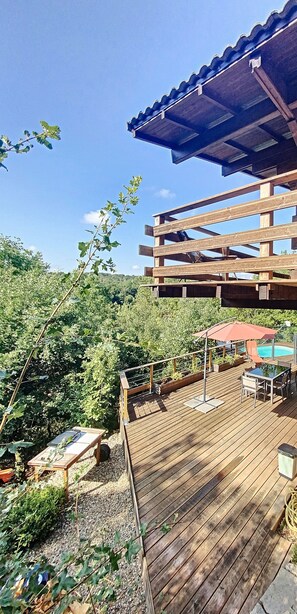 Relax on the deck with a clear view of the pool, surrounded by lush greenery.