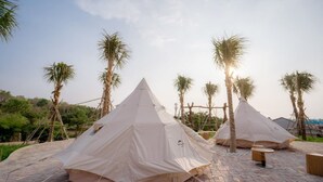 Two large, beige tents set up on a paved area with palm trees in the background. - Resort Đá Bàng Homestay & Restaurant (Ho Chi Minh City)