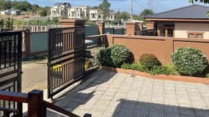 A residential area with a paved courtyard, a gated entrance, and houses in the background. - Resort Đá Bàng Homestay & Restaurant (Ho Chi Minh City)