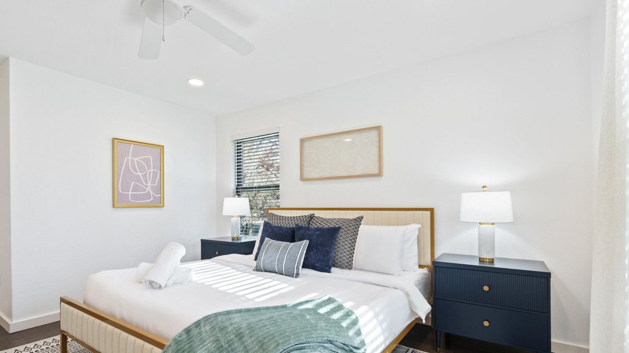 A neatly arranged bedroom with a bed, bedside tables, and a nightstand.