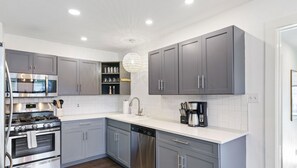 A modern kitchen with grey cabinets, stainless steel appliances, and a white countertop. - Broadmoor xxxxxxxxxx (Austin)