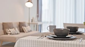 A modern dining area with a table set for two, featuring a striped tablecloth and dark bowls on plates.