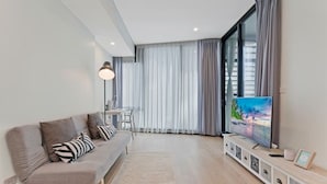 A modern living room with a sofa, a TV, and a dining area.