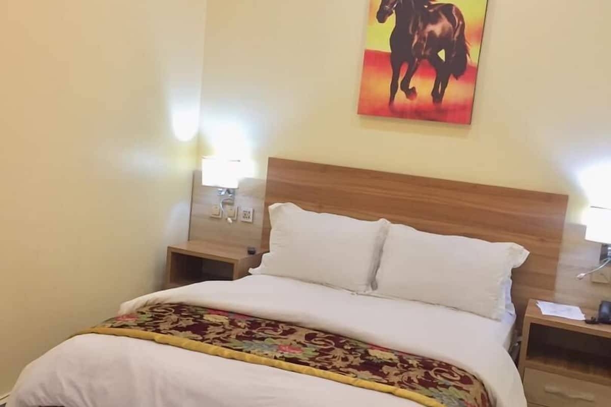 A neatly made bed with a floral bedspread, a wooden headboard, and a nightstand with a lamp.