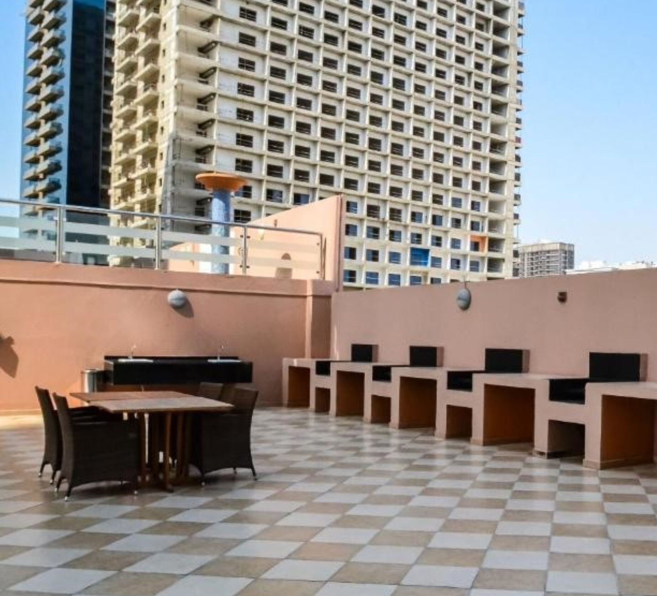 Une terrasse sur le toit dotée d’un sol à carreaux, d’une table à manger avec des chaises et d’un espace salon avec des bancs intégrés.