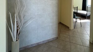 Un pasillo con suelo de baldosas, una pared lisa y una planta en maceta.