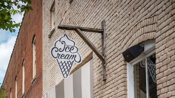 A brick building with a sign reading "Ice Cream" and outdoor seating with green chairs. - *Stylish 1BR Getaway w/ KING Bed + Patio + Wi-Fi (Lynchburg)