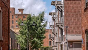 A narrow brick alley with a covered walkway, brick buildings, and a clear sky. - *Stylish 1BR Getaway w/ KING Bed + Patio + Wi-Fi (Lynchburg)