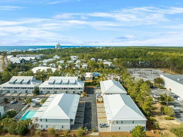A large hotel complex with multiple buildings, a central parking area, and a view of the ocean. - Nautical Compass F104-Cozy Townhome-Sleeps 7 (Santa Rosa Beach)
