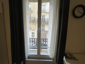 Um quarto com janela dando para um prédio com varandas.