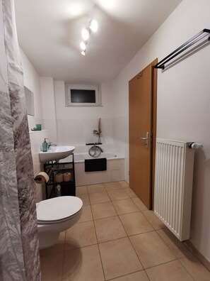 A bathroom with a toilet, sink, bathtub, and a shower curtain. - [r]auszeit, 65 qm Apartment, für Wanderlustige und Stadtbummler (Nittendorf)