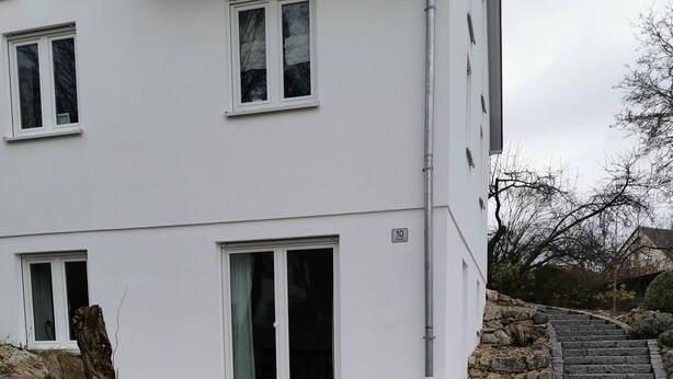 A modern building with a paved driveway, stone steps, and a stone wall. - [r]auszeit, 65 qm Apartment, für Wanderlustige und Stadtbummler (Nittendorf)