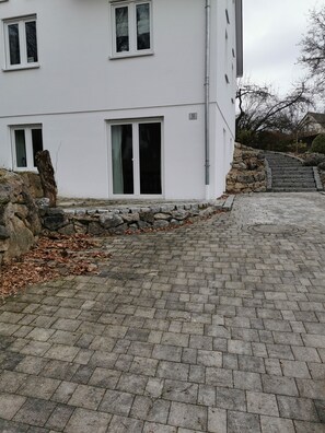 A modern building with a paved driveway, stone steps, and a stone wall. - [r]auszeit, 65 qm Apartment, für Wanderlustige und Stadtbummler (Nittendorf)