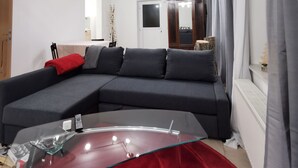 A modern living room with a sectional sofa, a glass coffee table, and a red accent rug. - [r]auszeit, 65 qm Apartment, für Wanderlustige und Stadtbummler (Nittendorf)