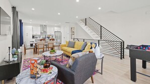 A modern living room with a sofa, coffee table, and a foosball table. - Stylish Stay with Rooftop Views and Garage Access (Charlotte)