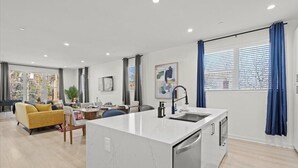 A modern apartment with a kitchen island, dining area, and living space. - Stylish Stay with Rooftop Views and Garage Access (Charlotte)