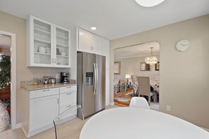 A modern kitchen with white cabinets, a stainless steel refrigerator, and a dining area with a table and chairs. - Family friendly home, sleeps 8, close to DC attractions.
New kitchen.  (Alexandria)