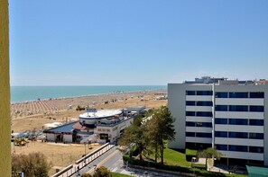 A coastal hotel with a beach view, a gas station, and a multi-story building. - Beachfront Two-room Flat With Side sea View (San Michele al Tagliamento)
