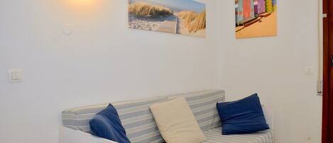 A room with a striped sofa, a small round table, and two wall-mounted light fixtures.