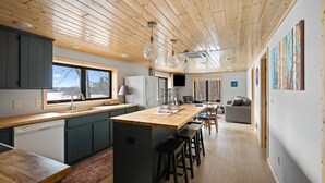 Een moderne keuken met houten plafond, een groot kookeiland met krukken en uitzicht buiten.