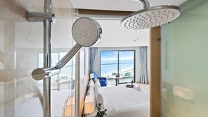A modern hotel room with a large window, a bed, a desk, and a shower area. - Cam Ranh Beach Resort near The Airport (Bac Cam Ranh)
