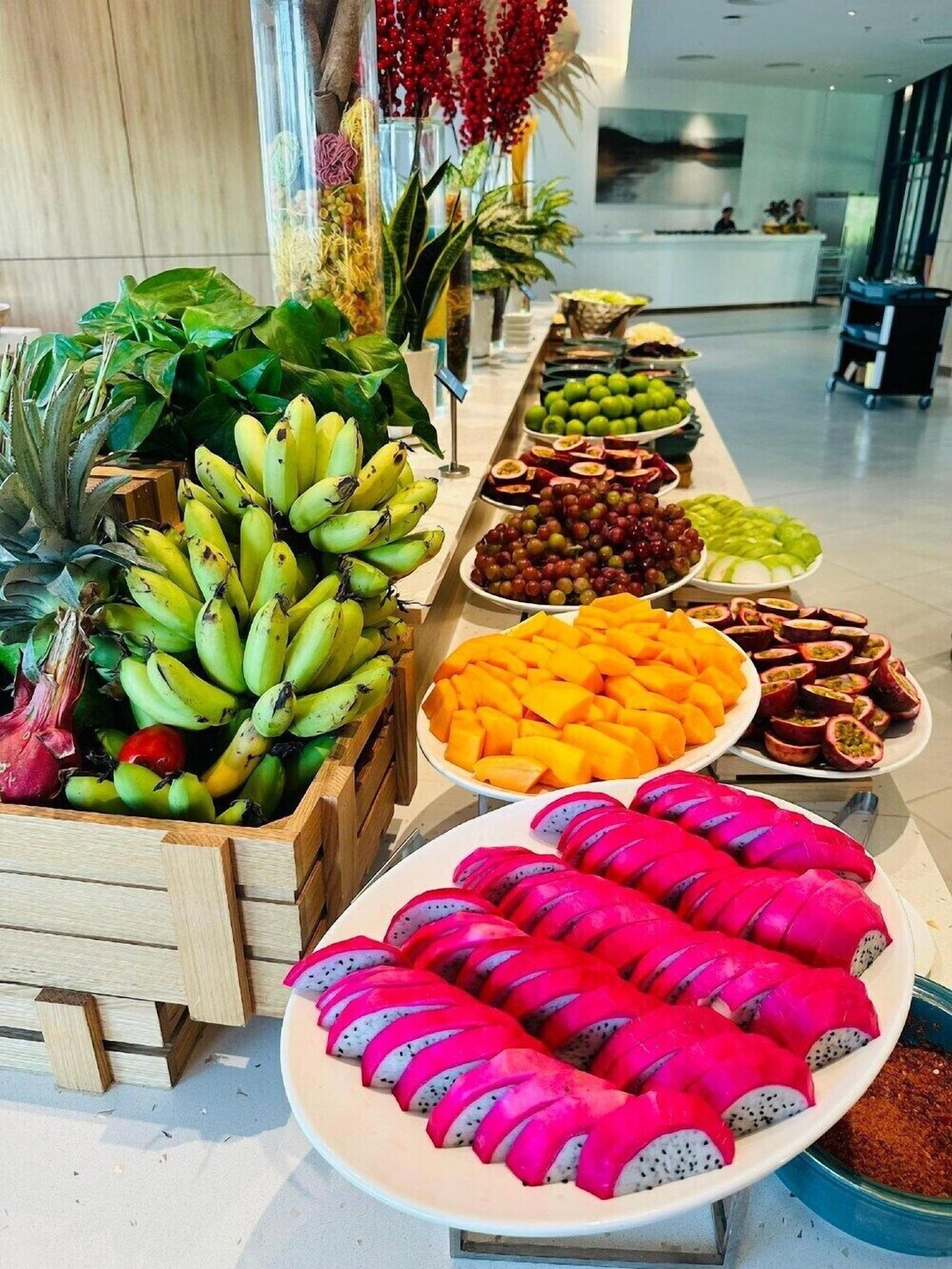 Un buffet proposant une variété de fruits et de légumes, notamment des bananes, des raisins et des fruits du dragon.