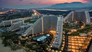 A modern hotel complex with multiple high-rise buildings, a central pool area, and well-lit pathways. - Cam Ranh Beach Resort near The Airport (Bac Cam Ranh)